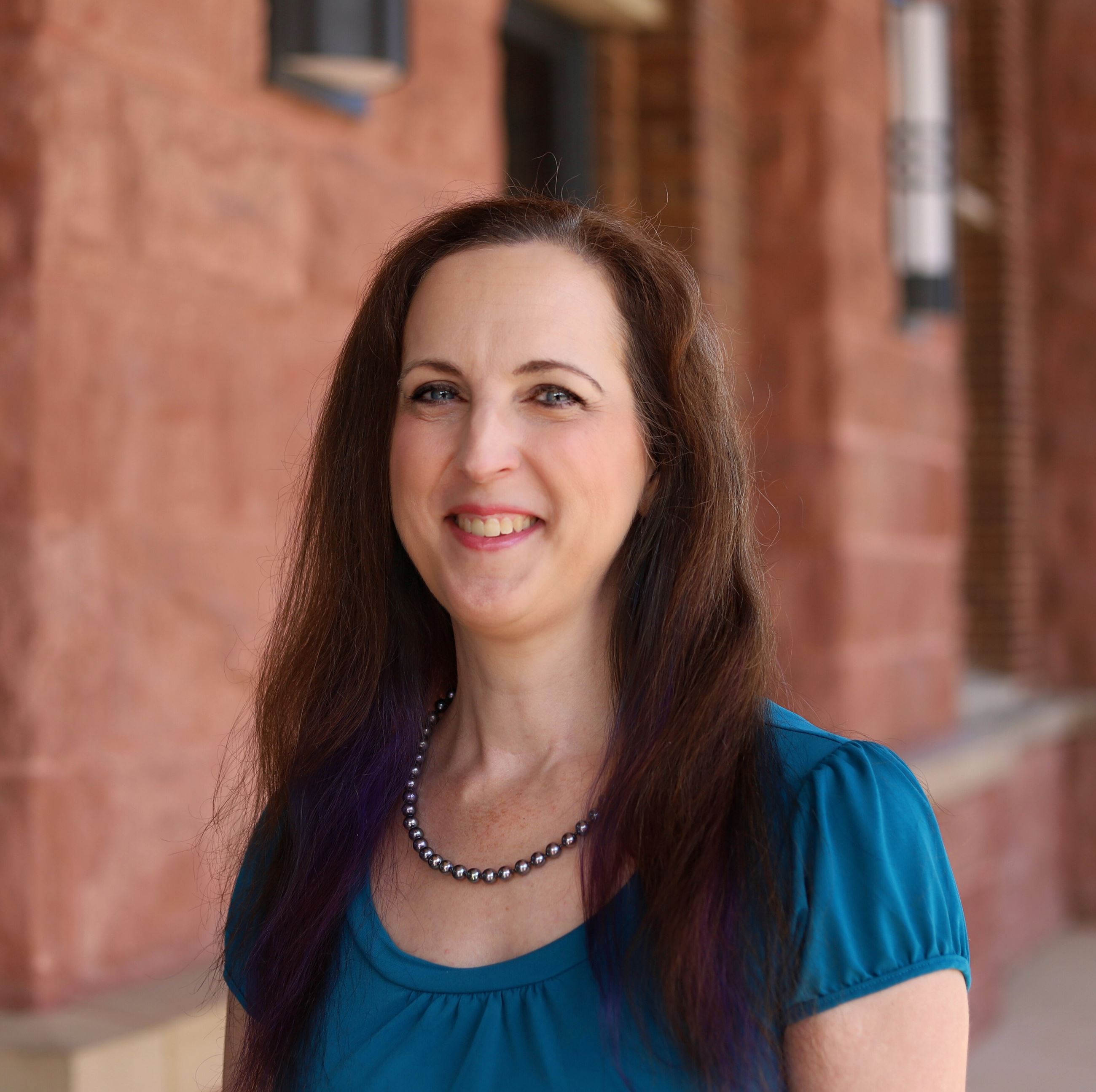 female with medium long brown hair wearing an aqua shirt 